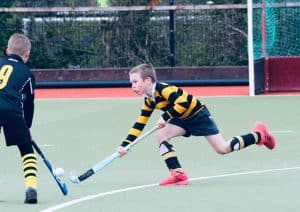 Young boys playing field hockey outdoors, focused on the game.