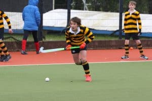 Young boy playing hockey on an outdoor field.