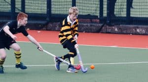 Two kids playing hockey on a sports court at Inchmarlo.