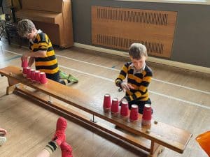 Two children playing with red cups at Inchmarlo nursery.