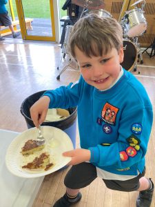 A cheerful young boy enjoys a slice of cake at Inchmarlo's community event, showcasing friendly atmosphere and family-friendly activities.