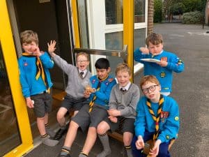 Children in blue scouting uniforms outside school.