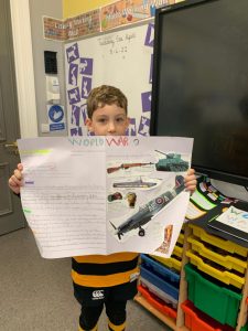 Young student holding Inchmarlo school project poster.