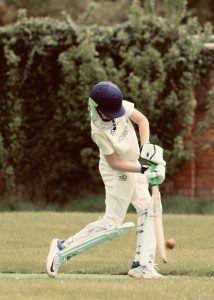 Youth cricket player at Inchmarlo golf and sports club practicing batting outdoors.