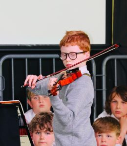 Young boy playing violin at Inchmarlo event, children performing music in an engaging setting.