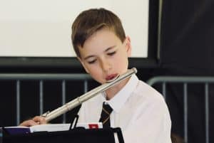 Young boy playing flute at Inchmarlo School in Scotland, focusing on music education and student activities.