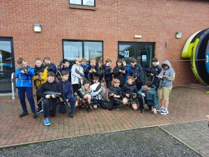Group of diverse children standing outside Inchmarlo care facility in front of red brick building.