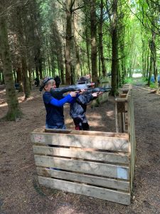 Children enjoying shooting range at Inchmarlo in a forest setting.