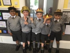 Young children celebrating in school with party hats, smiling and enjoying a festive event.