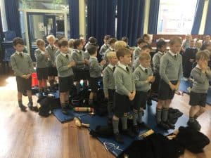 Children praying and reading in school assembly room, practicing mindfulness and developing spirituality.