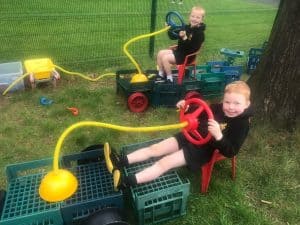 Children enjoying outdoor water play at Inchmarlo estate with water trucks and hoses.