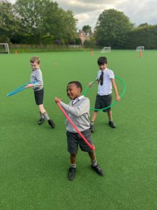 Three children playing with hoops on a lush green field at Inchmarlo.