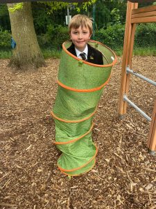 Boy in green slip-and-slide tunnel at Inchmarlo outdoor playground.