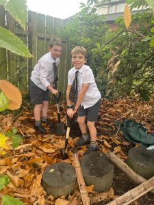 Two boys digging in a leaf-covered garden, playing outdoors at Inchmarlo.