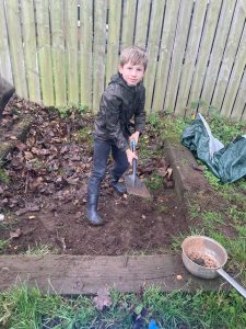 Young boy gardening at Inchmarlo estate with shovel and soil, family-friendly outdoor activity in scenic surroundings.