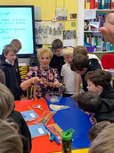 Children engaged in classroom activity with teacher and learning materials.