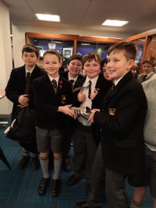 Students in uniform smiling with awards at Inchmarlo school event.