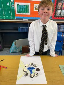 Young boy in school uniform displaying artwork at Inchmarlo School.