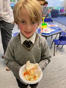 Smiling boy holding a decorated cake at Inchmarlo school event.