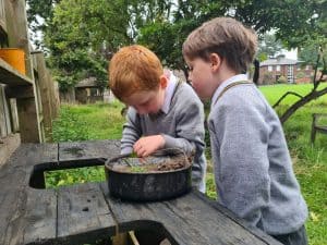 Two children exploring nature at Inchmarlo in Scotland, enjoying outdoor activities in a lush green environment.