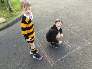 Two children drawing with chalk on playground pavement at Inchmarlo.