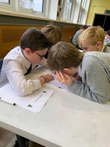 Group of children collaborating at school desk, engaging in educational activity, bright classroom setting.