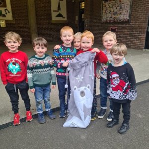 Group of cheerful children holding a festive polar bear poster outside Inchmarlo school.