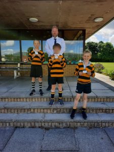 Young boys in striped rugby shirts at Inchmarlo Golf Academy, Scotland, enjoying outdoor activities.