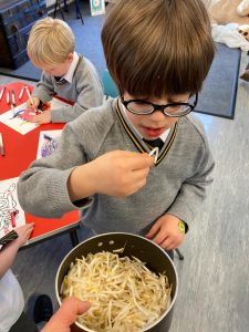 Young boy tasting food at school event, engaging in a culinary activity.