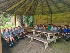 Children sitting inside a wooden gazebo at Inchmarlo, enjoying outdoor activities and nature.