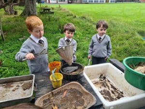 Three children exploring outdoor sensory play at Inchmarlo school.